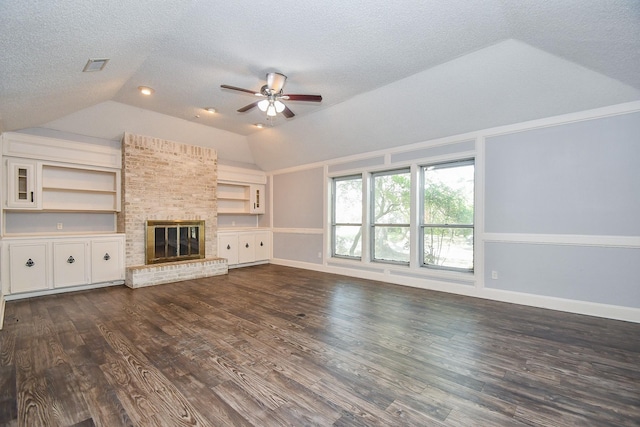 unfurnished living room with a textured ceiling, dark wood-style floors, lofted ceiling, a brick fireplace, and ceiling fan