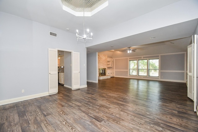 unfurnished living room featuring dark wood-type flooring, ceiling fan with notable chandelier, visible vents, and baseboards