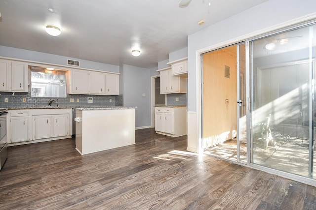 kitchen featuring visible vents, a kitchen island, decorative backsplash, dark wood-style floors, and white cabinets