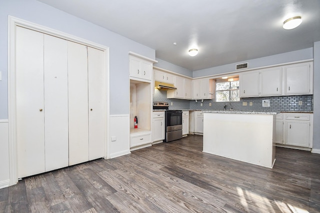 kitchen with tasteful backsplash, visible vents, under cabinet range hood, range with electric stovetop, and dark wood-style floors