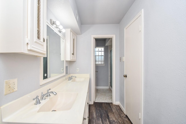 bathroom featuring double vanity, a shower stall, baseboards, and a sink