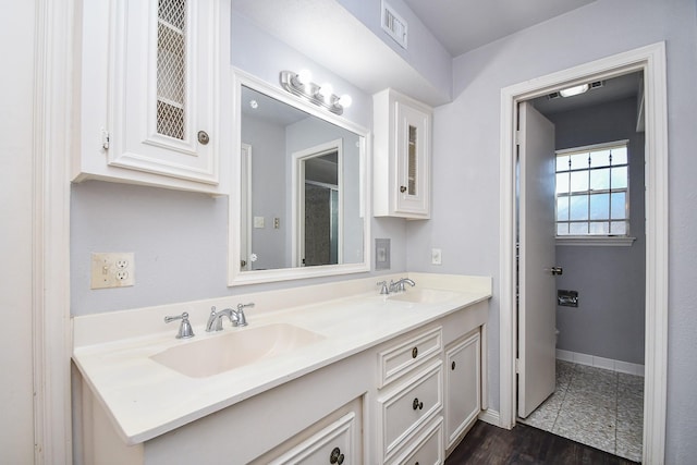 bathroom featuring double vanity, baseboards, visible vents, and a sink