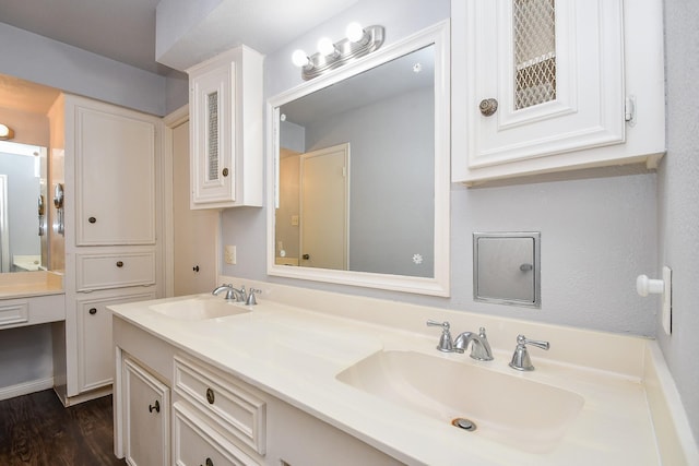 bathroom with double vanity, wood finished floors, and a sink