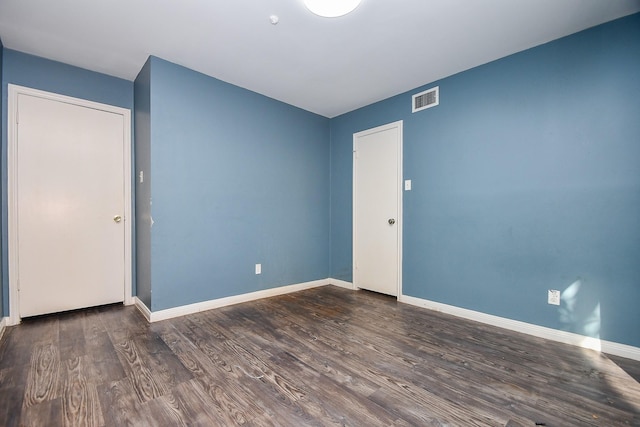 unfurnished room featuring wood finished floors, visible vents, and baseboards