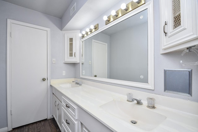 full bathroom featuring double vanity, wood finished floors, visible vents, and a sink