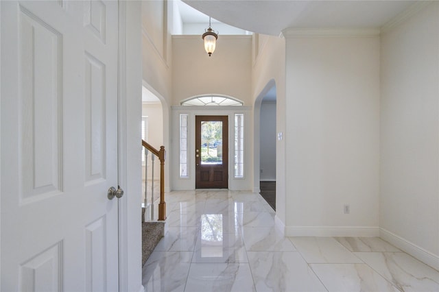 entryway with ornamental molding, arched walkways, marble finish floor, and baseboards