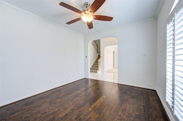 spare room with arched walkways, wood finished floors, ceiling fan, and ornamental molding