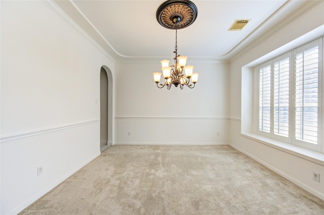 carpeted spare room featuring visible vents, baseboards, ornamental molding, an inviting chandelier, and arched walkways