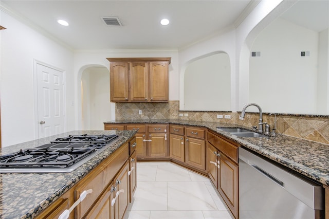 kitchen featuring dark stone counters, arched walkways, a sink, stovetop with downdraft, and stainless steel dishwasher