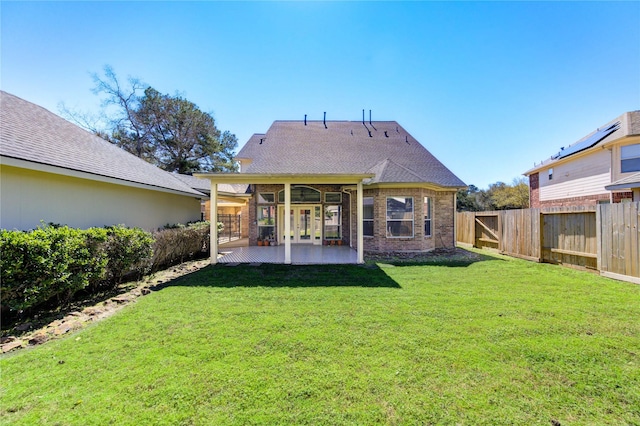 back of property featuring brick siding, a fenced backyard, a lawn, and a patio area