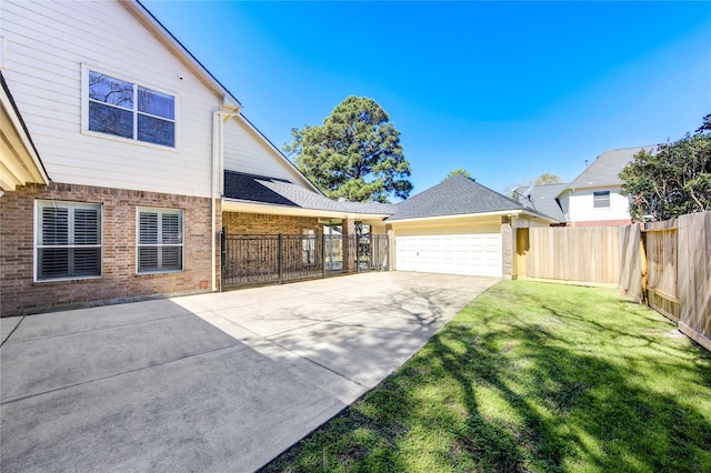 exterior space featuring fence, driveway, an attached garage, a lawn, and brick siding