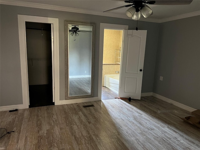 unfurnished bedroom with visible vents, crown molding, baseboards, wood finished floors, and a ceiling fan