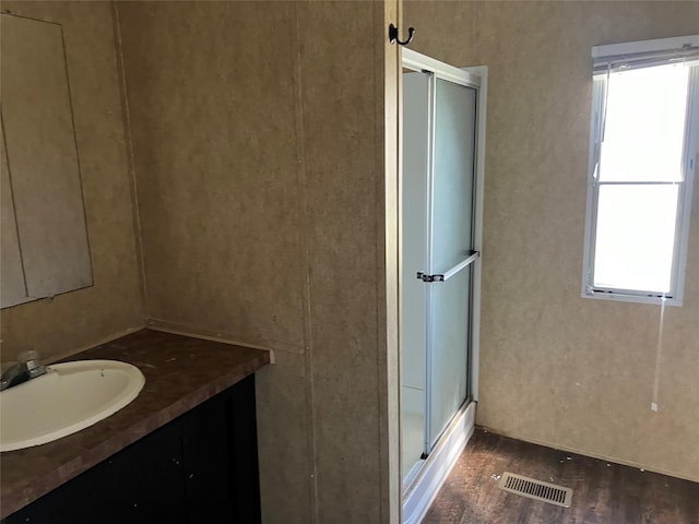 bathroom featuring visible vents, a shower stall, vanity, and wood finished floors