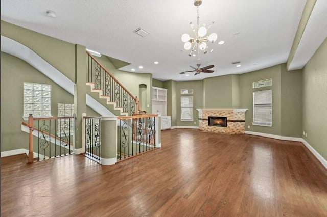 unfurnished living room featuring a glass covered fireplace, visible vents, baseboards, and wood finished floors