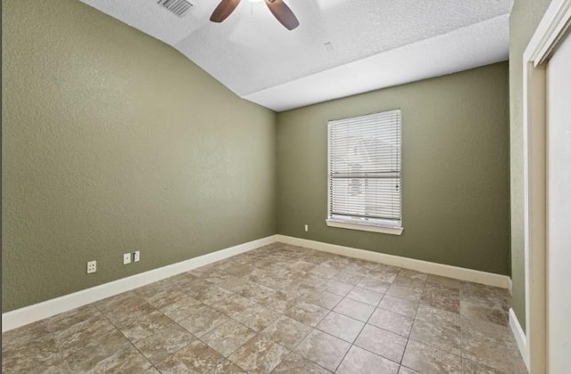 spare room with a ceiling fan, visible vents, a textured wall, and baseboards