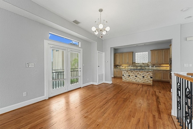 6132 Maxie St, Houston, TX 77007 - unfurnished living room featuring a chandelier, light wood finished floors, baseboards, and plenty of natural light