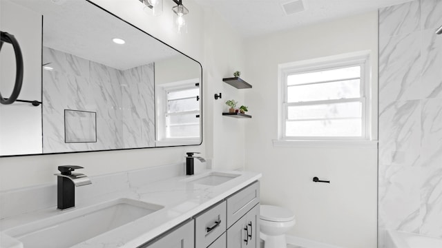 bathroom with a sink, visible vents, toilet, and double vanity