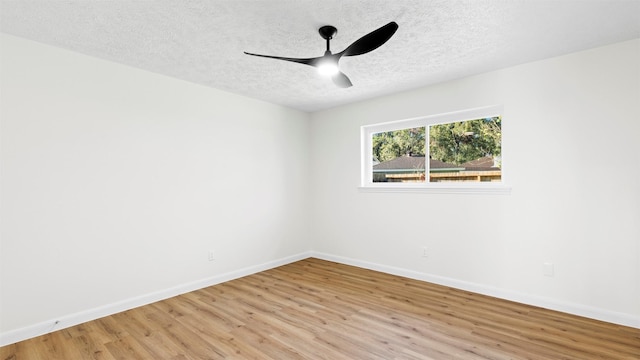 spare room featuring light wood-style flooring, a ceiling fan, baseboards, and a textured ceiling