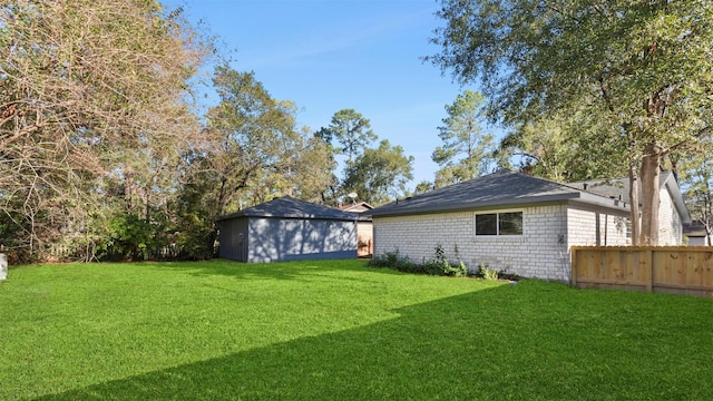 view of yard featuring a storage unit, an outdoor structure, and fence