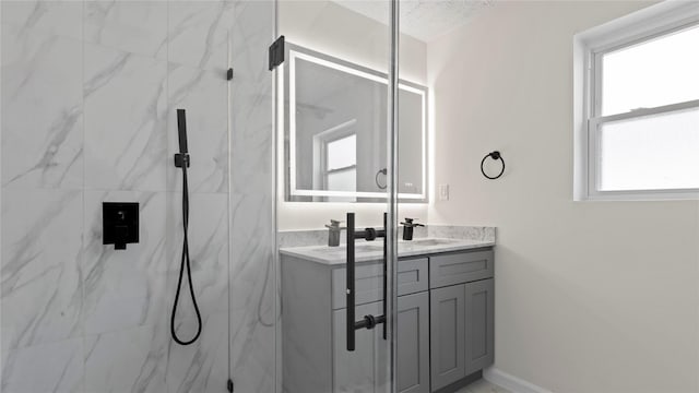 bathroom featuring a marble finish shower, a sink, baseboards, and double vanity