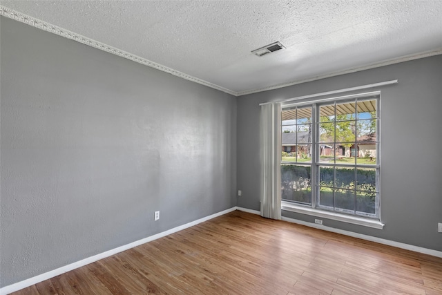 spare room featuring a textured ceiling, wood finished floors, visible vents, and baseboards