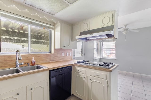 kitchen with light tile patterned floors, a sink, stainless steel gas stovetop, under cabinet range hood, and dishwasher