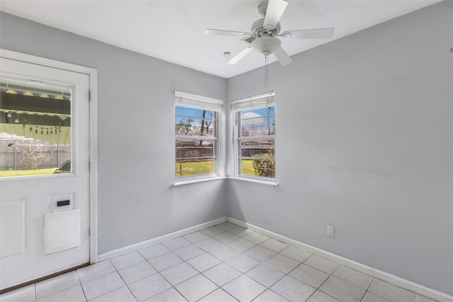 empty room featuring light tile patterned floors, baseboards, and a ceiling fan