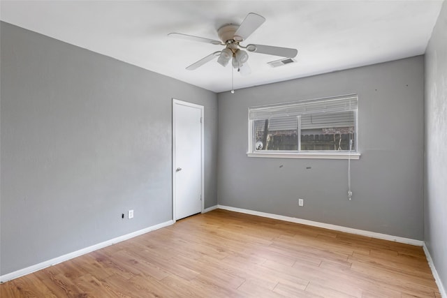 spare room featuring light wood-style flooring, visible vents, baseboards, and ceiling fan