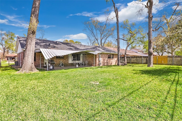 back of house featuring a yard, brick siding, a patio area, and fence