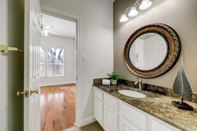 bathroom with baseboards, a ceiling fan, wood finished floors, and vanity