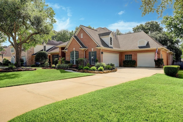 view of front facade with driveway, roof with shingles, a front yard, a garage, and brick siding