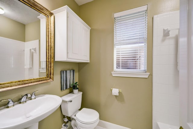 full bathroom featuring baseboards, toilet, a bath, a shower, and a sink