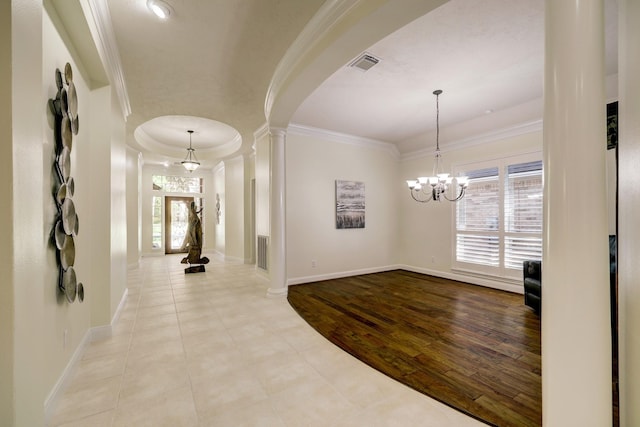 corridor with visible vents, decorative columns, arched walkways, crown molding, and a chandelier