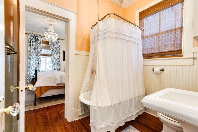 1411 13th St, Galveston, TX 77550 - full bath featuring wood finished floors, wainscoting, a chandelier, a shower with shower curtain, and connected bathroom