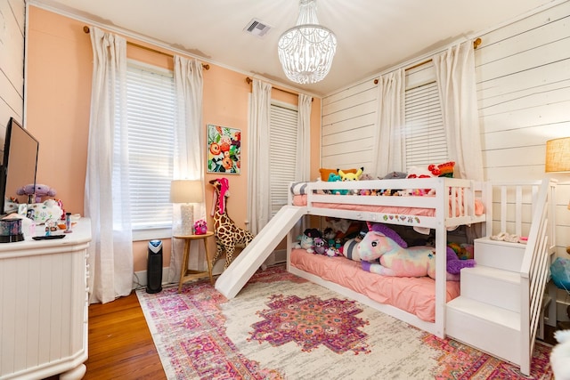 1411 13th St, Galveston, TX 77550 - bedroom featuring multiple windows, a chandelier, wood walls, and wood finished floors