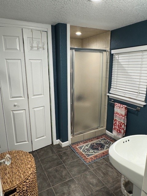 1411 13th St, Galveston, TX 77550 - full bathroom with a shower stall, a textured ceiling, tile patterned flooring, and baseboards