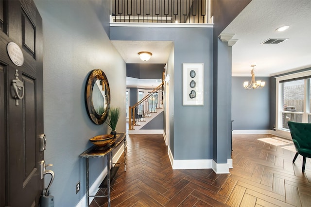 foyer with an inviting chandelier, stairway, baseboards, and visible vents