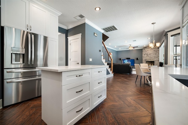 kitchen with visible vents, stainless steel fridge, open floor plan, and crown molding