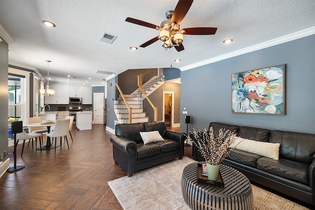 living room with a textured ceiling, ceiling fan, stairs, and ornamental molding