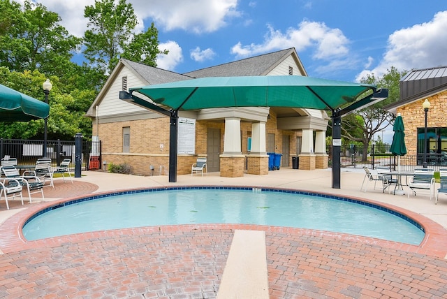 pool with a patio area and fence