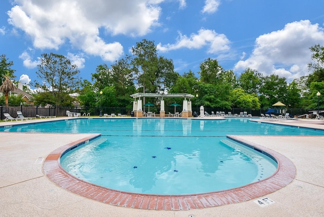 community pool with a patio area and fence