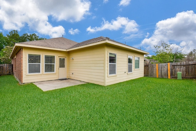 back of house with a fenced backyard, a patio, a shingled roof, and a yard