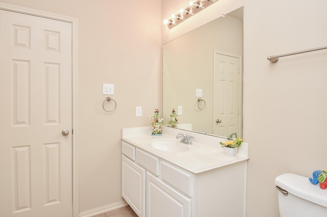 half bath featuring tile patterned floors, toilet, vanity, and baseboards