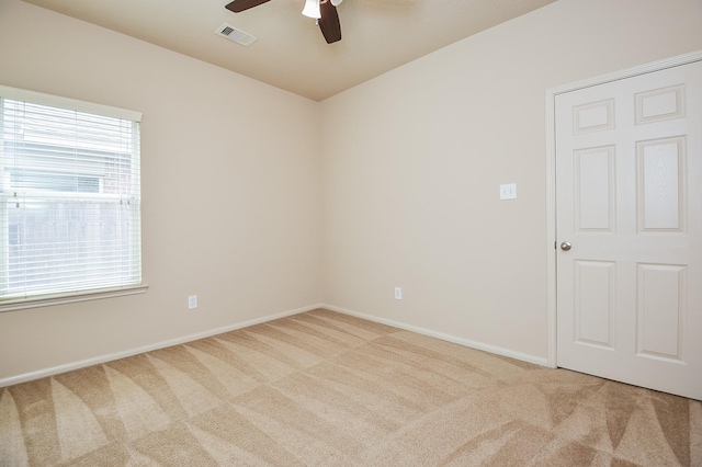 carpeted empty room with visible vents, baseboards, and ceiling fan