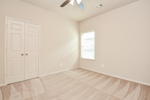 carpeted empty room with visible vents, baseboards, and ceiling fan