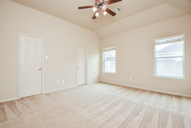 spare room featuring visible vents, baseboards, vaulted ceiling, light carpet, and a ceiling fan