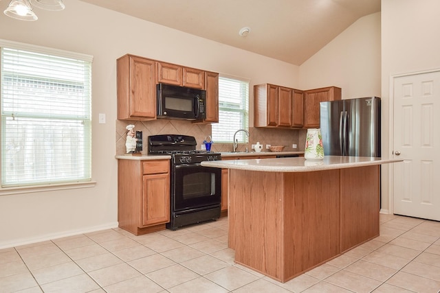 kitchen with light tile patterned floors, lofted ceiling, black appliances, and light countertops