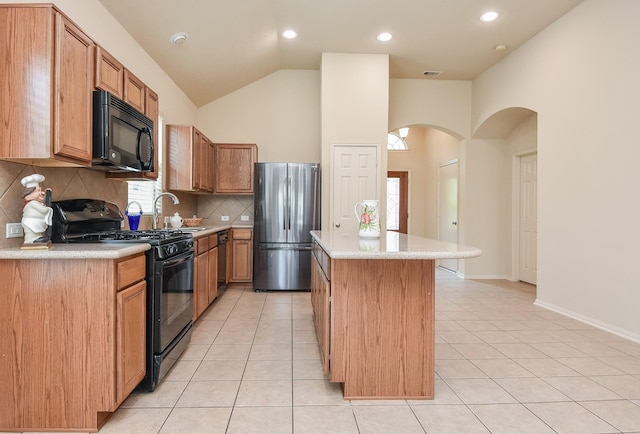 kitchen with light tile patterned floors, a kitchen island, arched walkways, and black appliances