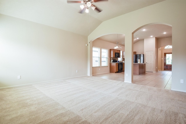 unfurnished living room with light tile patterned floors, high vaulted ceiling, arched walkways, light carpet, and ceiling fan with notable chandelier