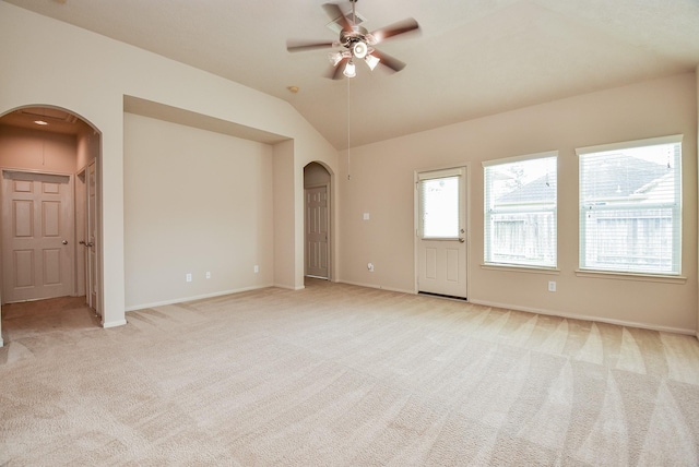 unfurnished room featuring arched walkways, light carpet, a ceiling fan, and vaulted ceiling